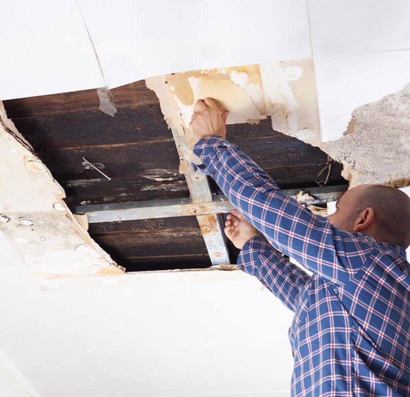 Contractor repairing drywall ceiling, addressing hole and damage, showcasing craftsmanship in construction services by Framing to Drywall.