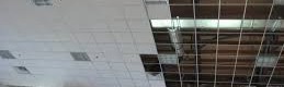 Ceiling grid installation with partially installed acoustic tiles, showcasing drywall and framing work by Framing to Drywall.