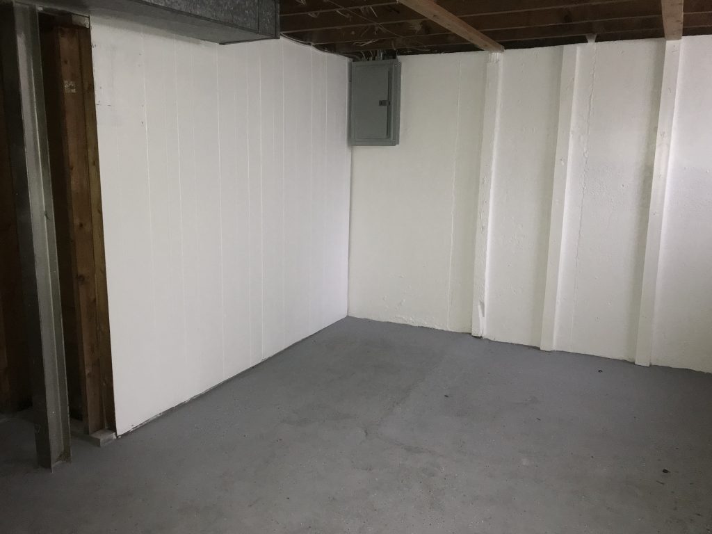 Interior view of a freshly painted basement with white walls and a concrete floor, showcasing framing and drywall installation by Framing to Drywall.